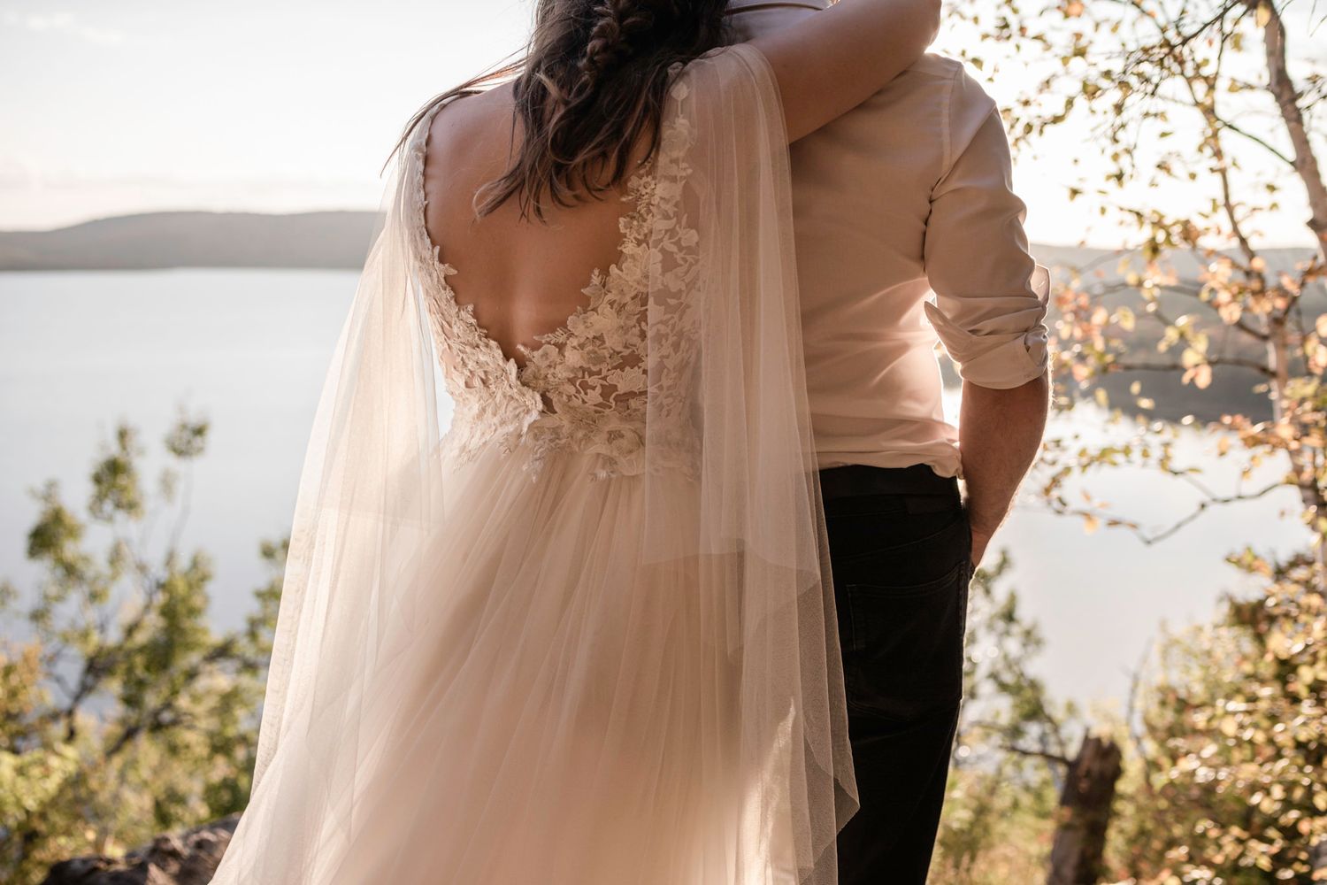 Eloping couple share an intimate embrace while overlooking the lake below in Mont Tremblant, Quebec, Canada.