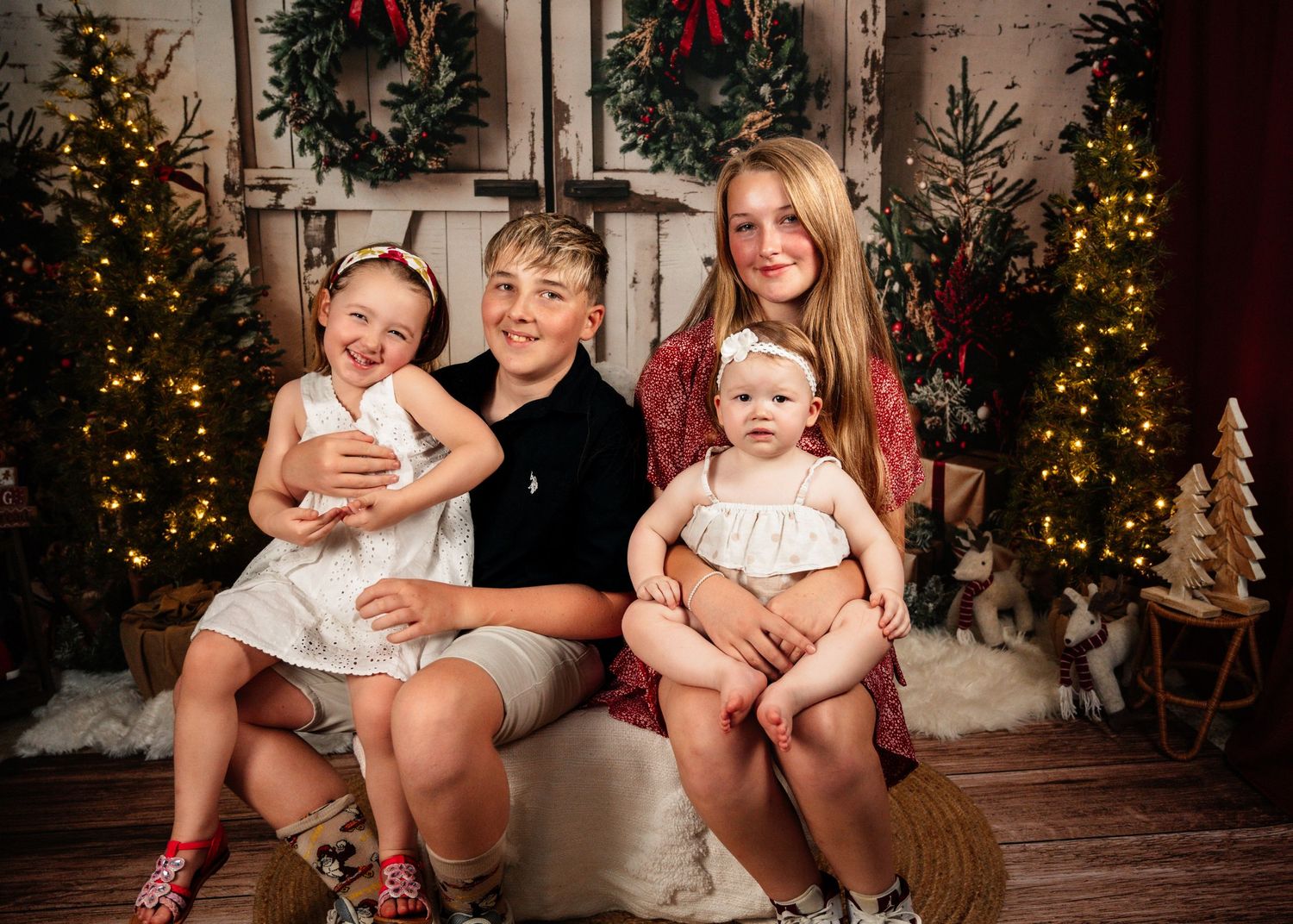 Family portrait with holiday decor featuring Christmas trees, wreaths and twinkling lights.
