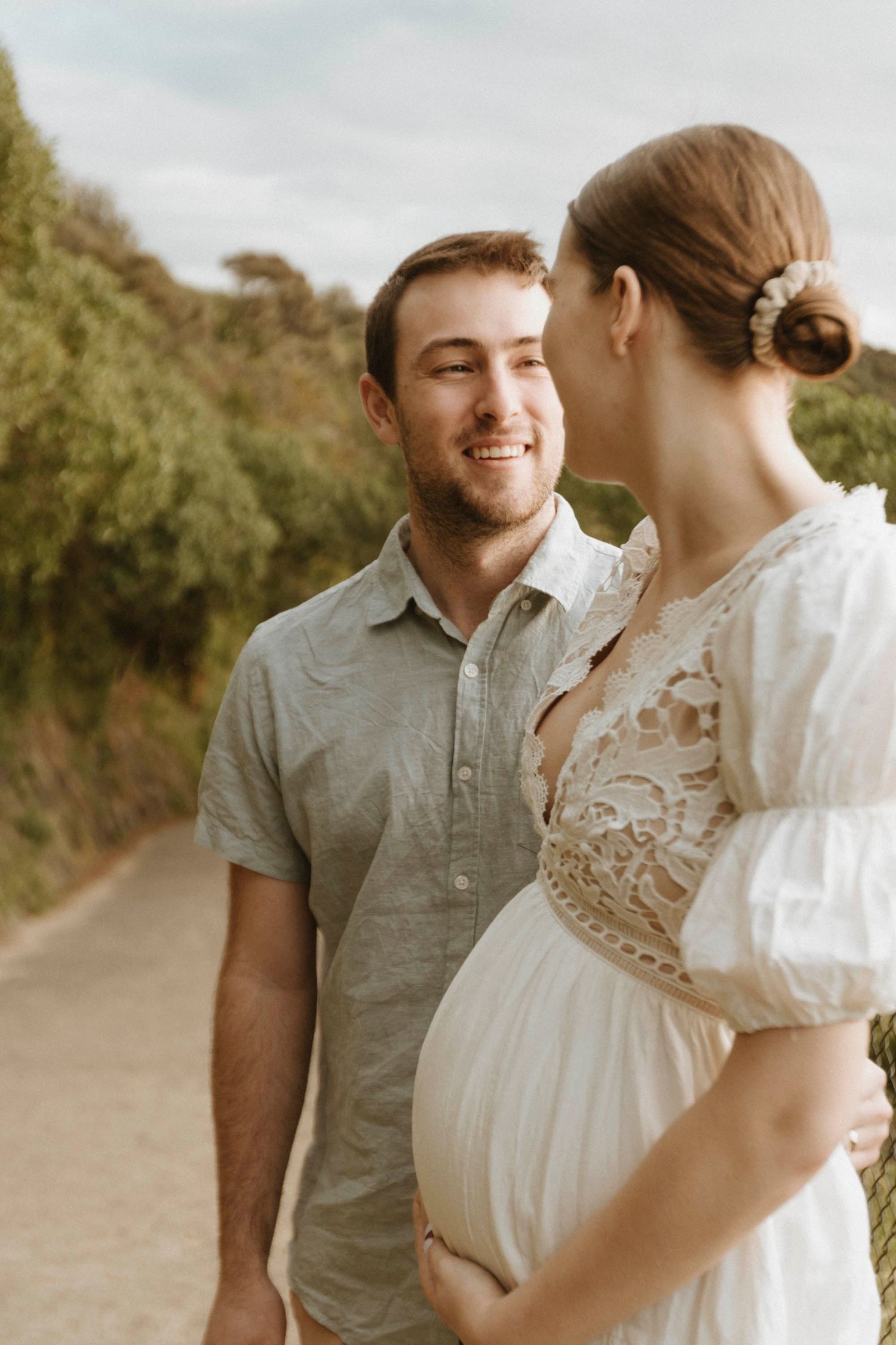 Tender maternity moment shared on a sunlit nature path.