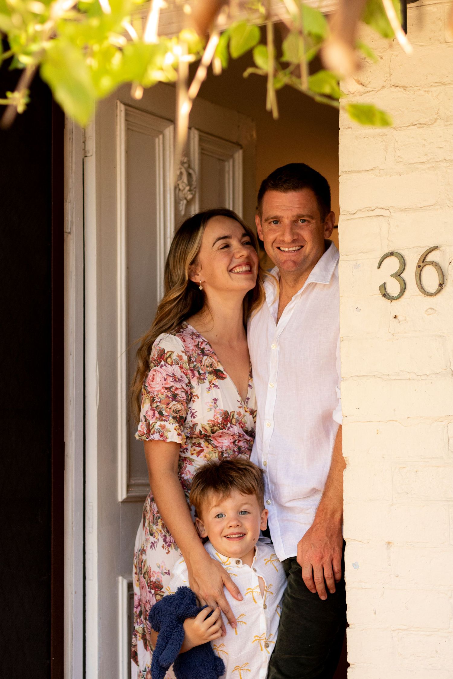 A happy family poses together at their front door marked number 36.
