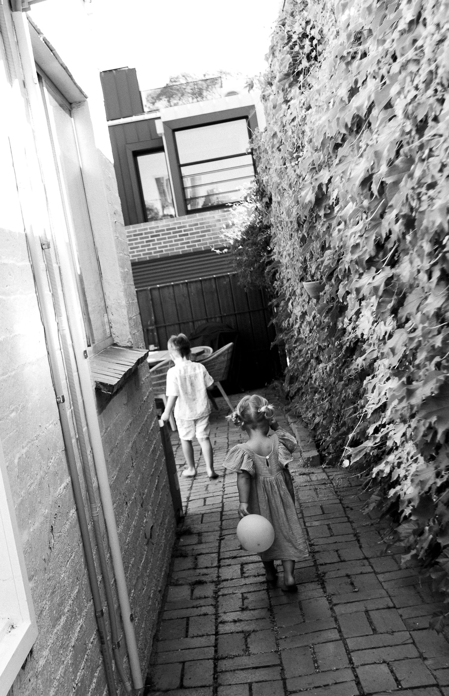 Black and white photo of children playing in a narrow brick pathway.
