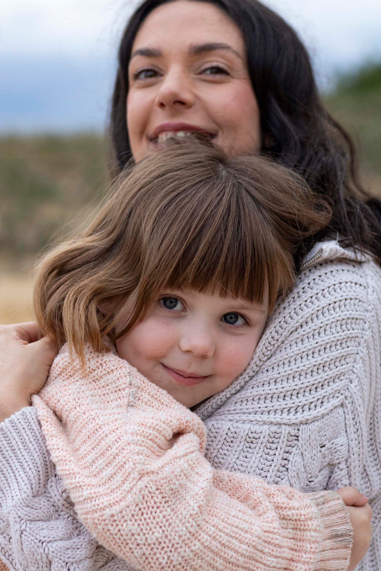 A close-up of a parent and young child in cozy knit sweaters sharing a tender moment together.