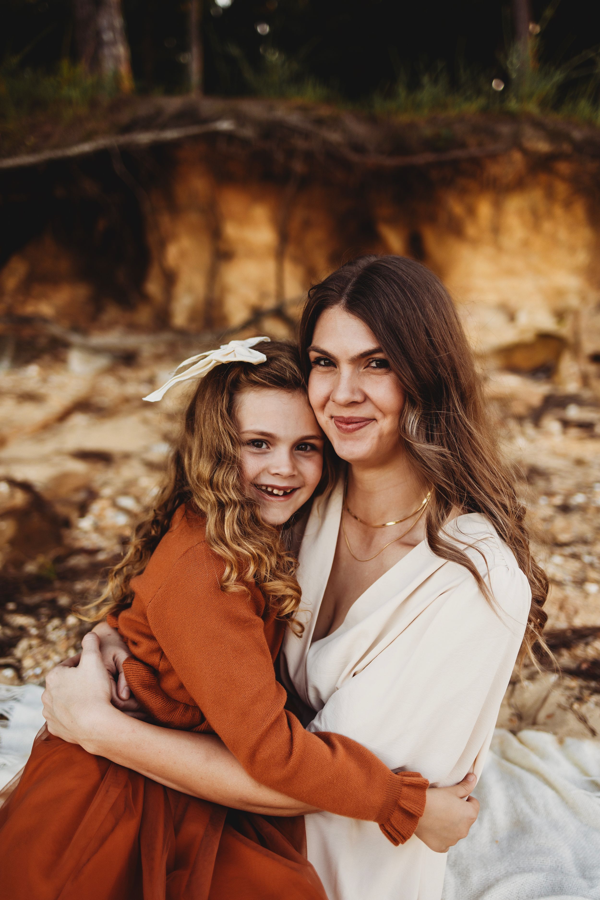 Tender embrace between parent and child wearing coordinating rust and cream colored outfits.