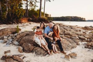 Family relaxing together on rocky beach during golden hour.