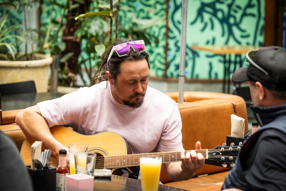 A man plays guitar at a cafe table