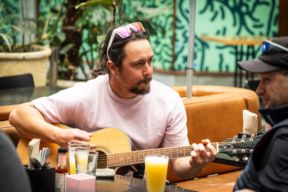 A man plays guitar at a cafe table