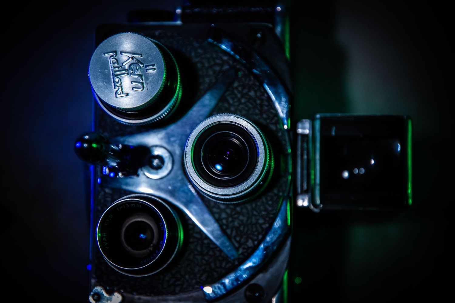 Macro shot of vintage camera lenses and mechanisms with dramatic blue lighting.