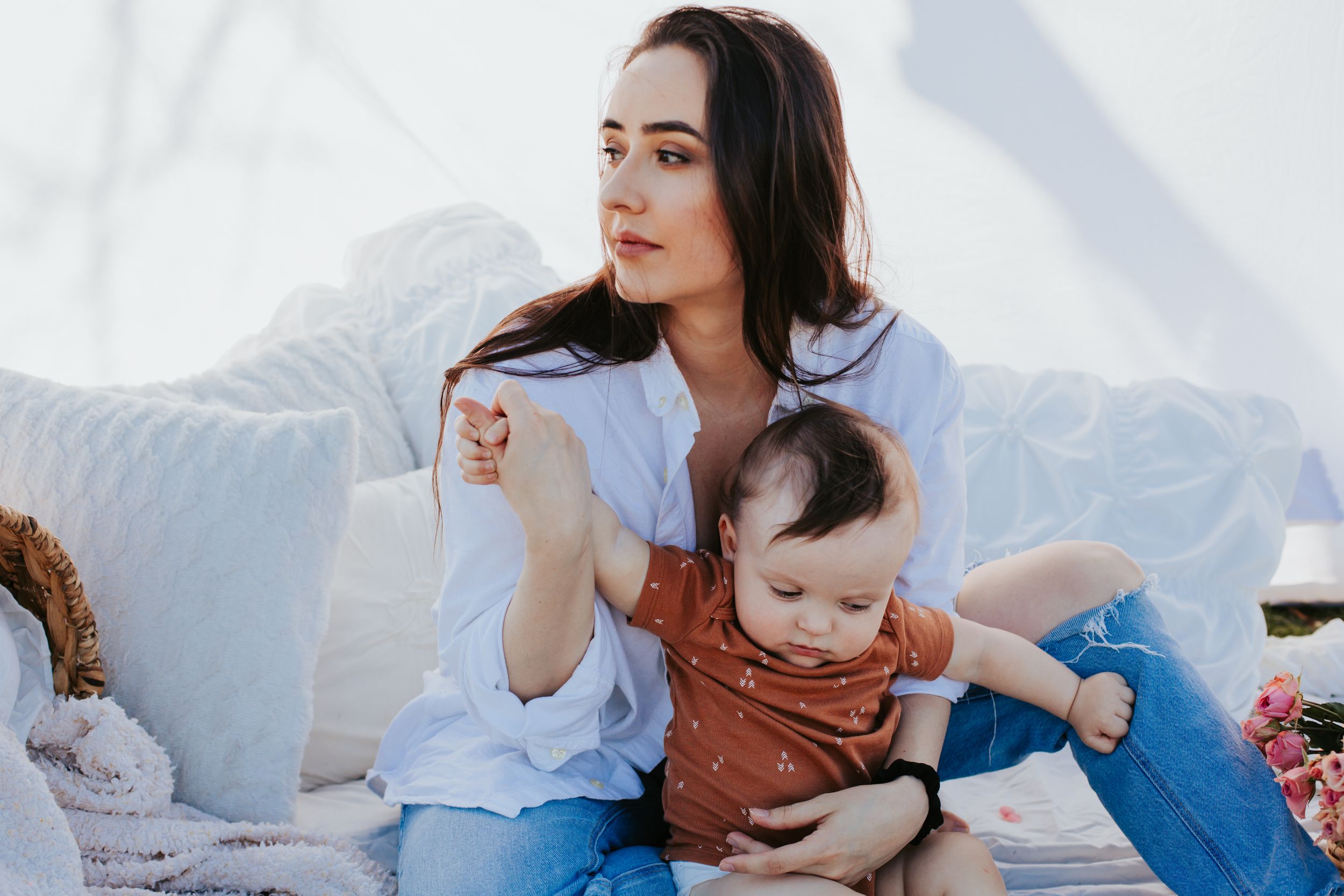 A parent and baby relax together on a white couch.