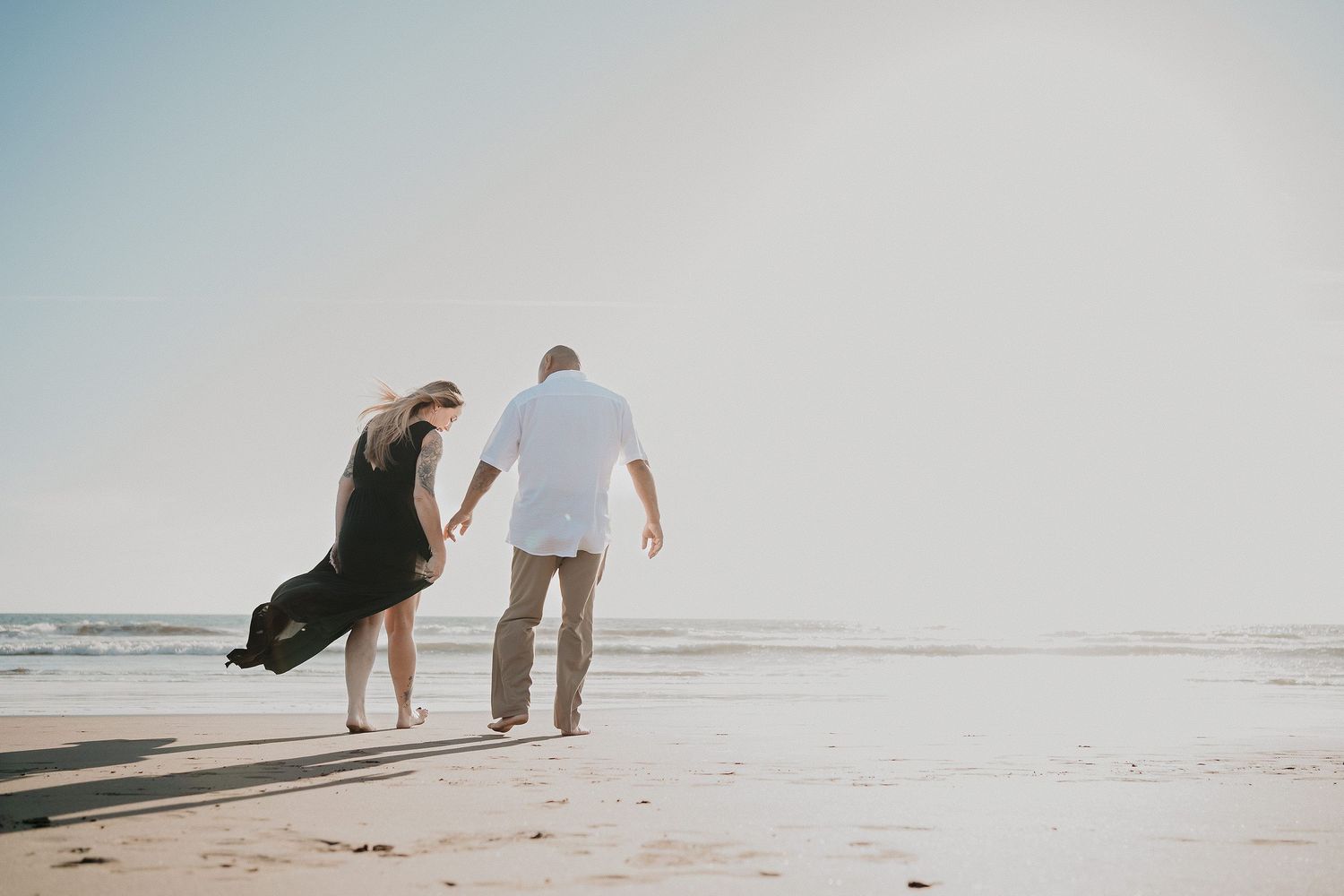 Pareja caminando en la playa al atardecer durante sesión casual en Mazatlán