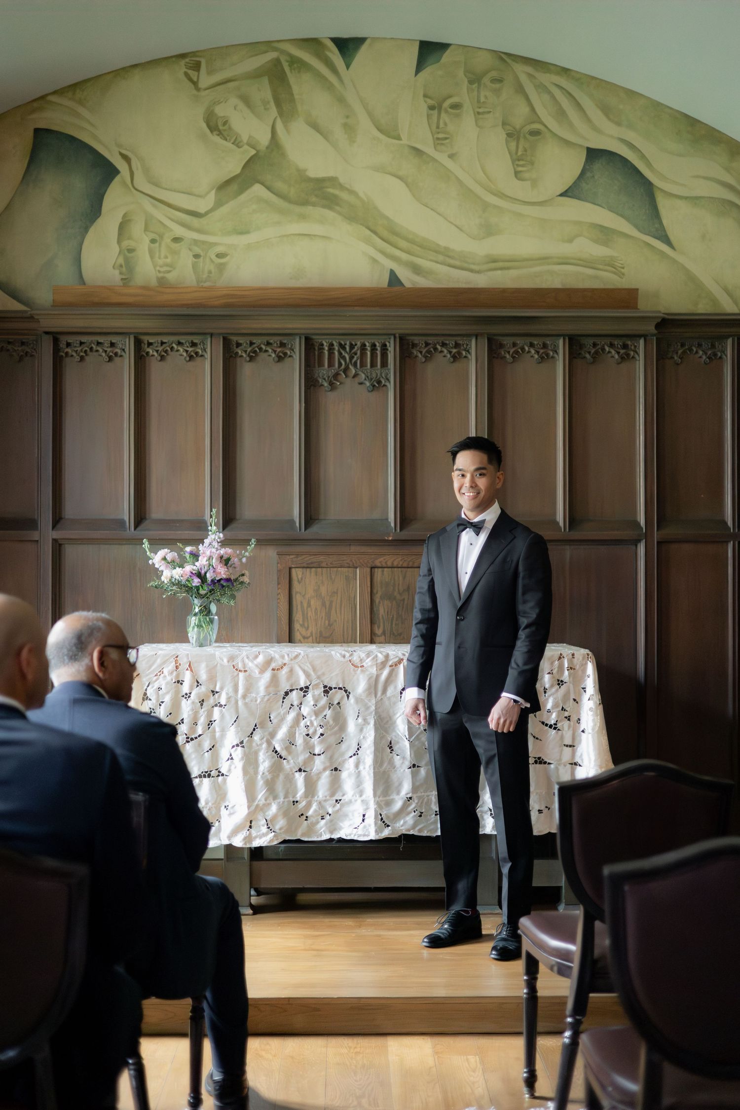 A formal wedding ceremony setup in a chapel with wood paneling and painted ceiling mural.
