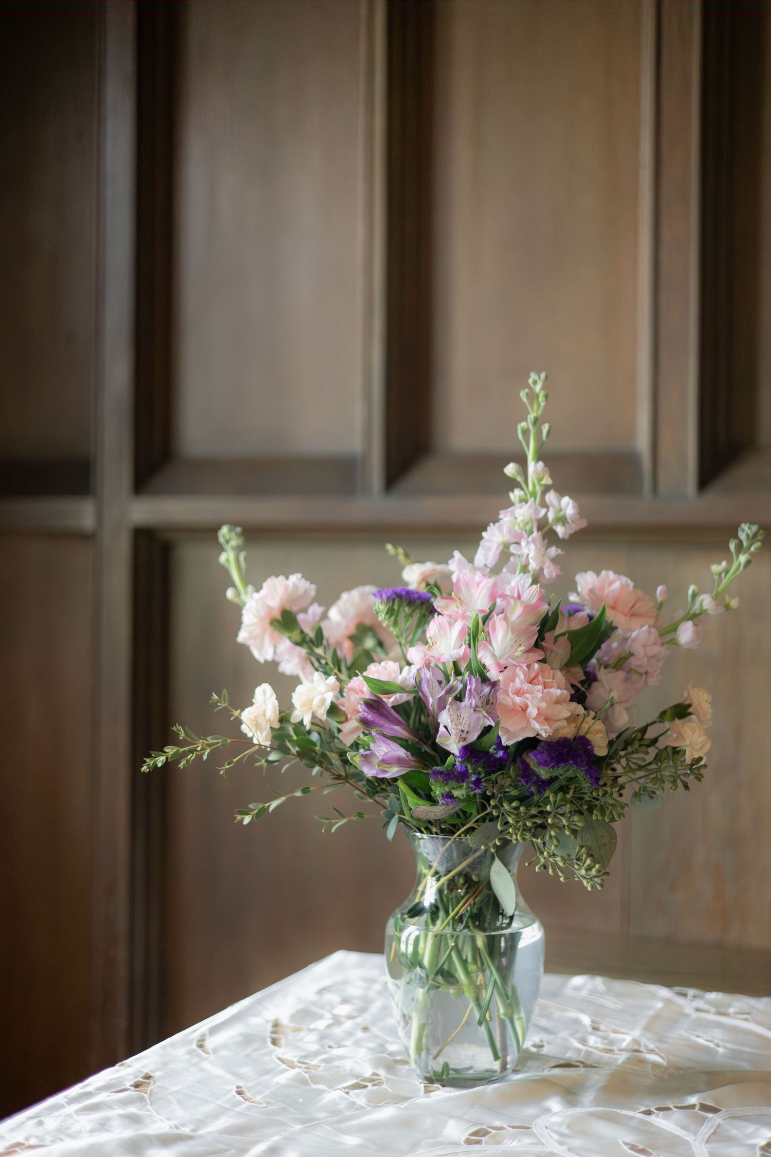 A spring flower arrangement in a glass vase featuring pink and purple blooms.