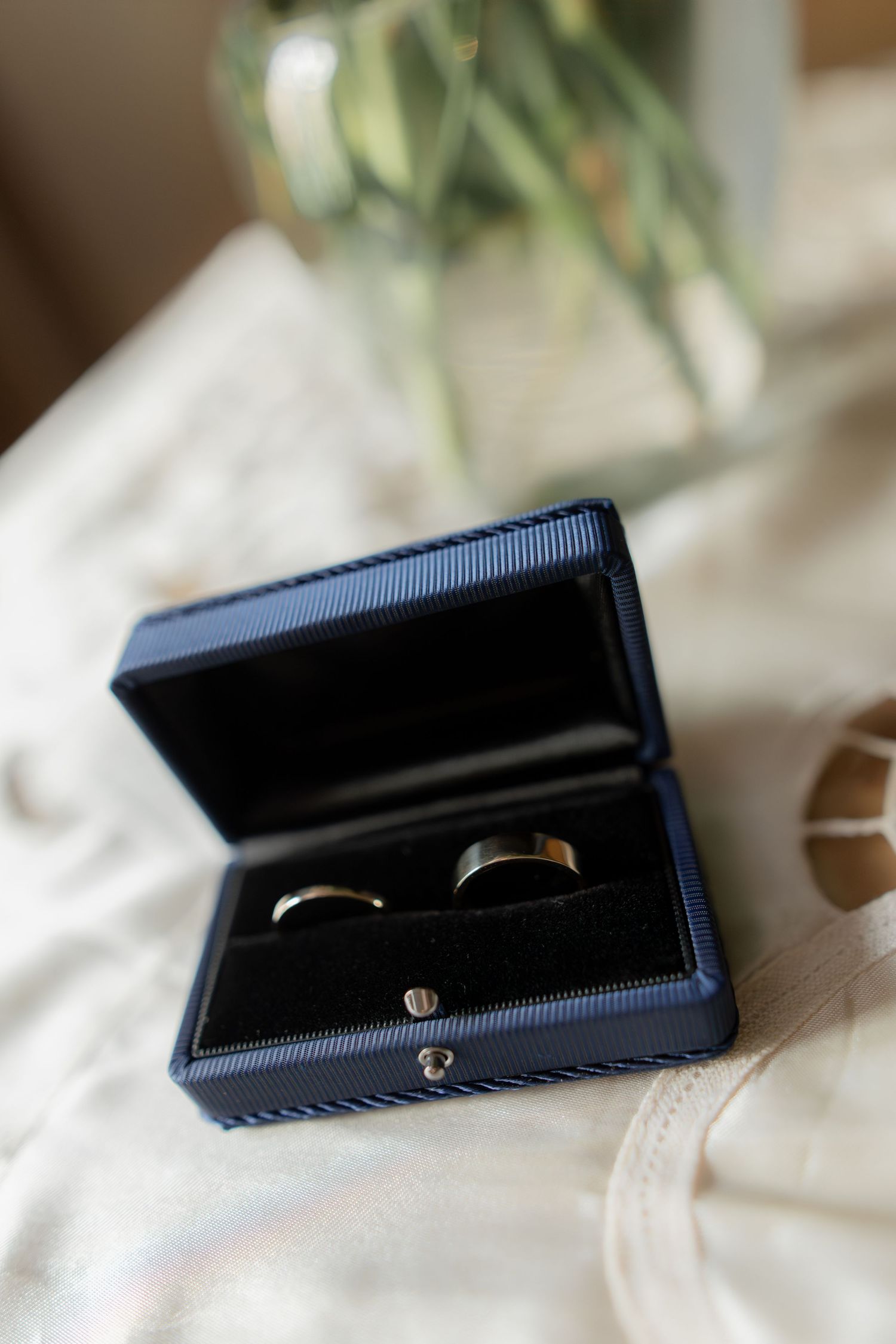 Two wedding bands nestled in a navy blue ring box on white fabric.