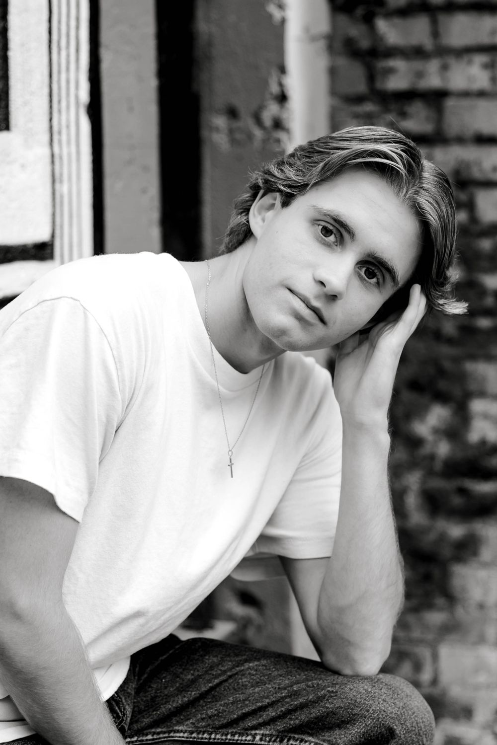 Black and white portrait of a young man resting head on hand with a thoughtful expression.