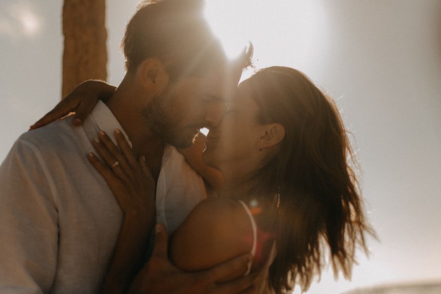 Romantic backlit couple sharing tender moment in golden sunlight.