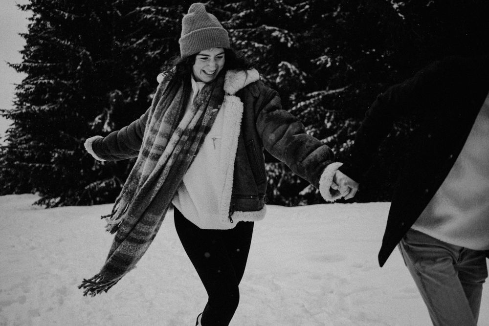 Winter scene with person in beanie and scarf playing in snowy forest.
