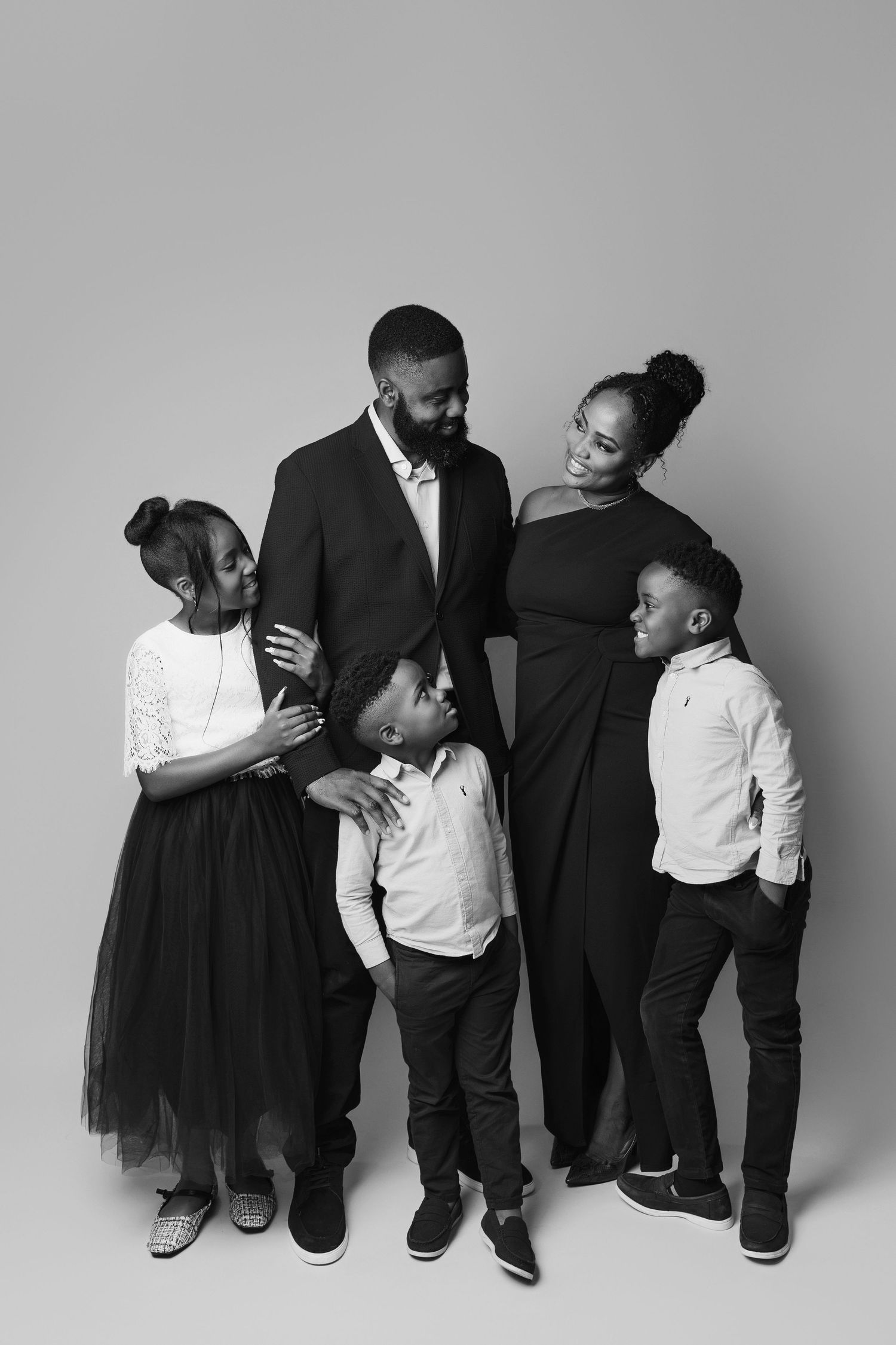 Black and white photo series showing family members in matching formal attire posing together against a studio backdrop.