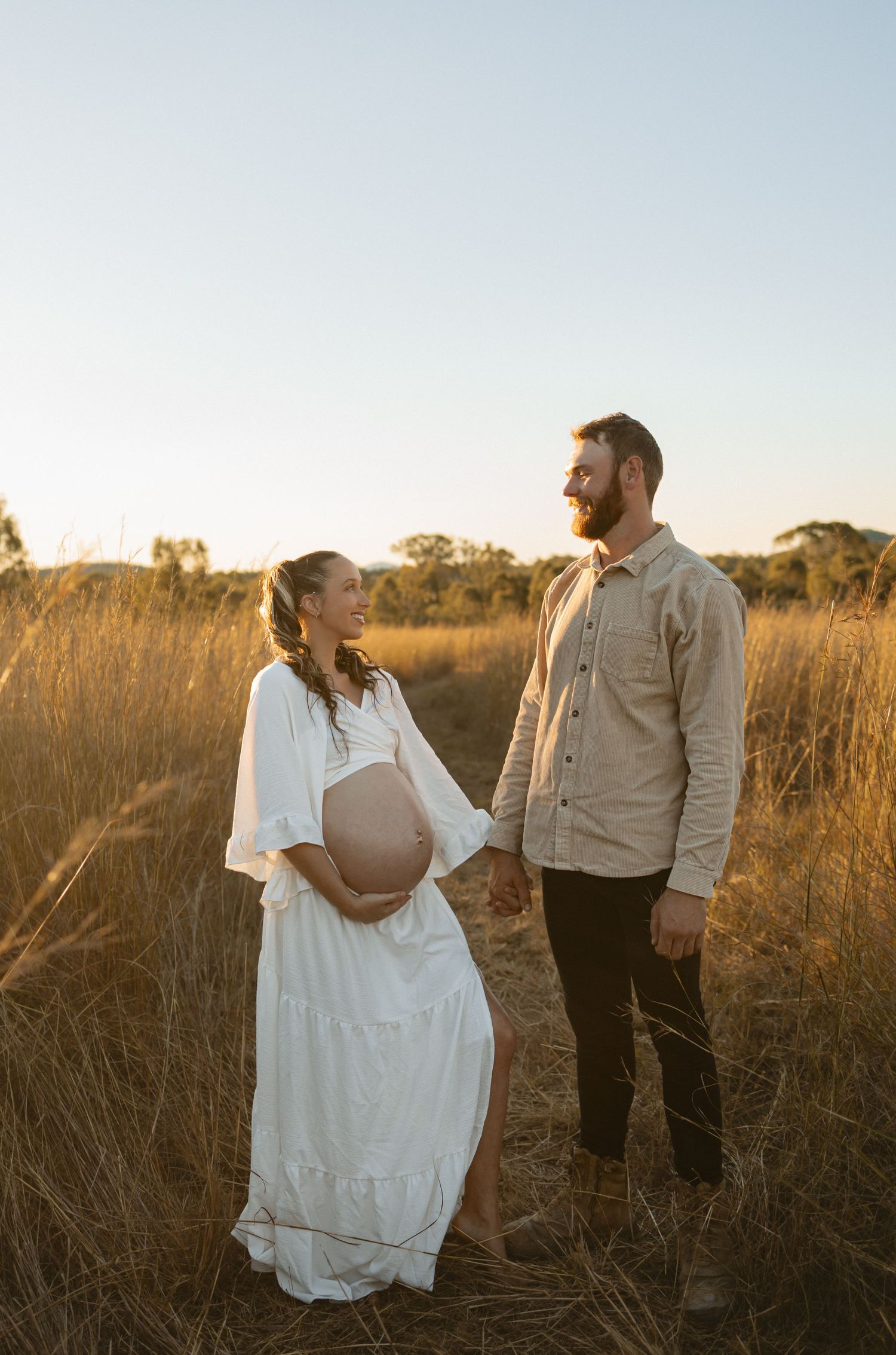 A couple shares a romantic sunset moment in a golden field of tall grass.