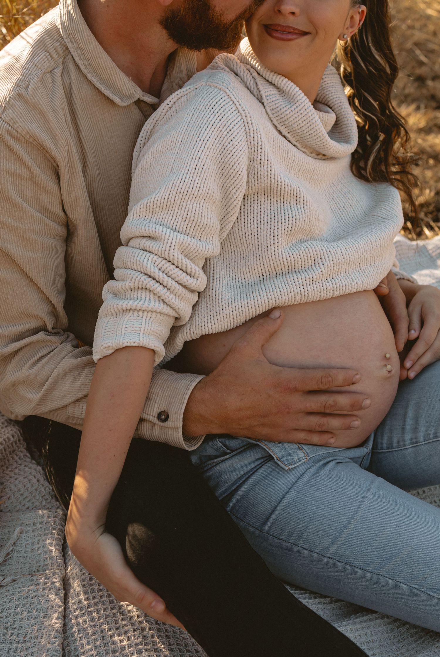 A warm and intimate pregnancy photo series captures tender moments between an expectant couple at sunset.