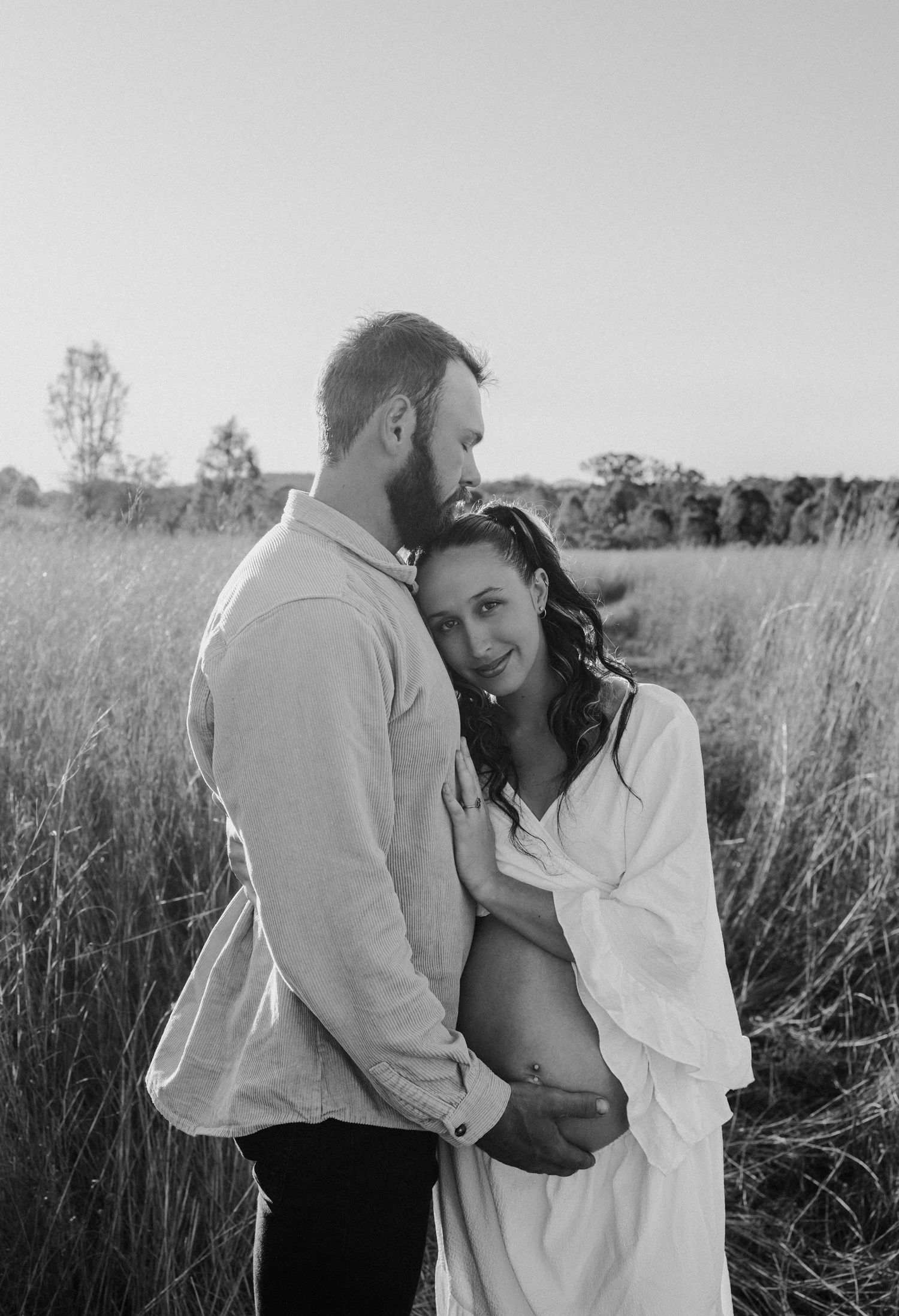 A romantic black and white photo sequence showing a couple embracing in a meadow of tall grass during sunset.