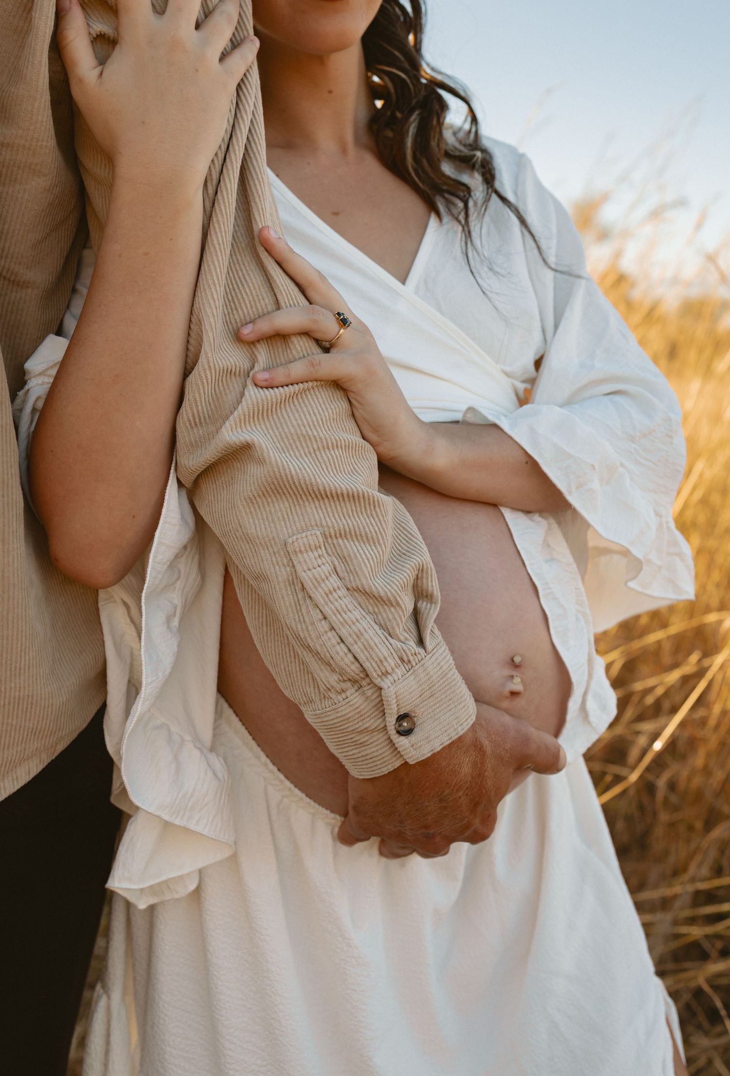A series of intimate maternity photos showing a white dress and gentle poses in golden sunlight.