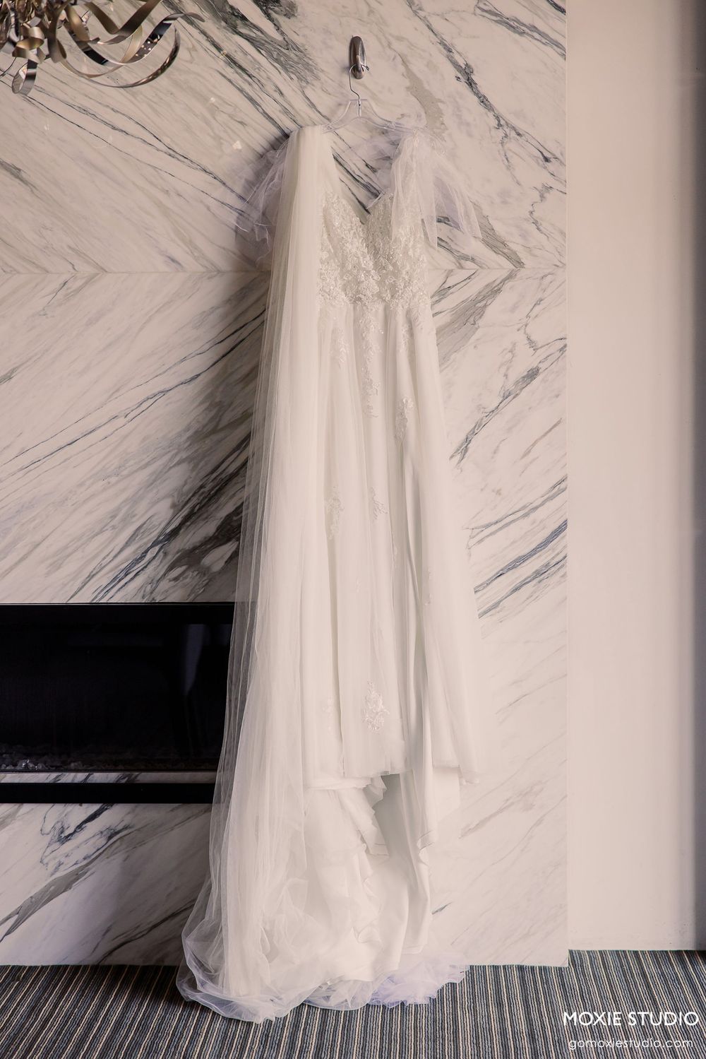 A white wedding dress hangs against a marbled wall in a sequence of four similar photos.