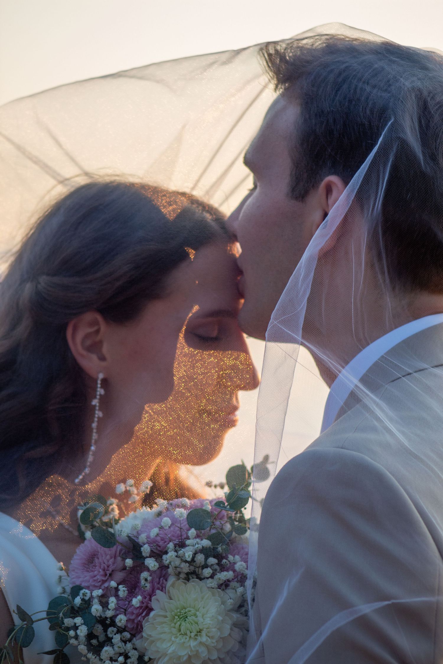 Utah couple under veil. groom kissing brides forehead against an Utah sunset.