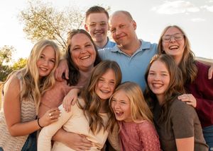 A joyful family poses together outdoors for a warm sunset portrait in American Fork, Utah.