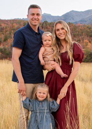 Family in coordinated outfits posing together in autumn field with Utah mountain backdrop in Provo.