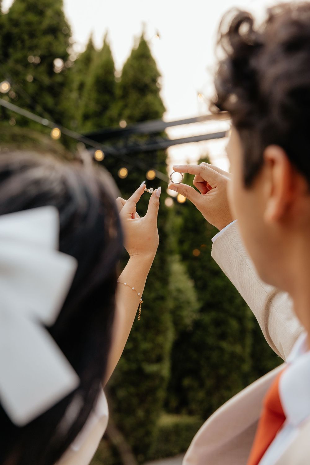 Bride and groom making heart shape with fingers at outdoor wedding reception.