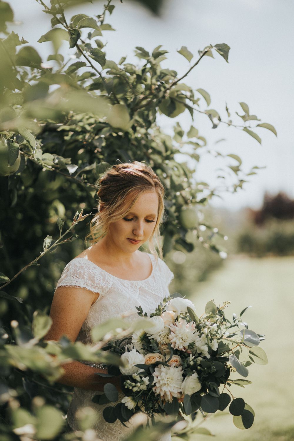 Bride admiring bouquet at Swans Trail Farm wedding, rustic outdoor venue in Washington