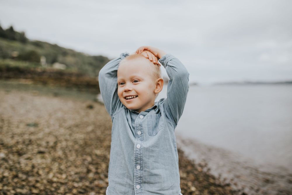 Young boy playfully laughing during family photoshoot on Alki beach by Seattle photographer