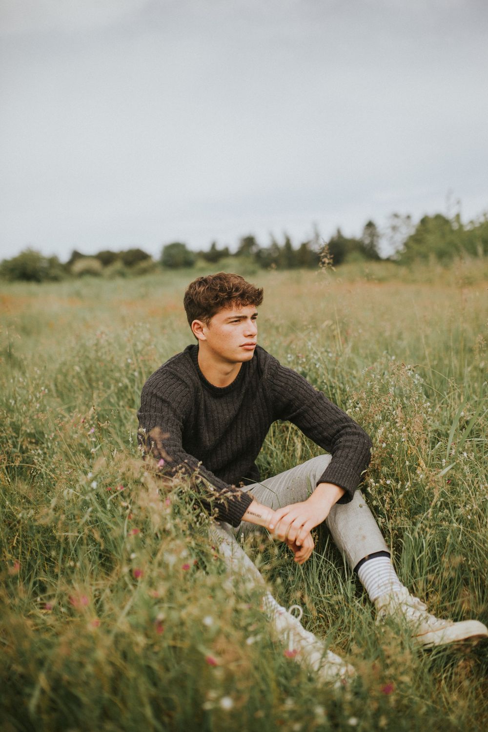 Stylish male senior portrait in grassy field taken in Seattle park by lifestyle photographer