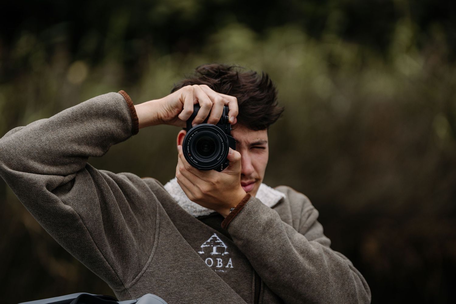 Person in gray sweatshirt taking photo with professional camera.