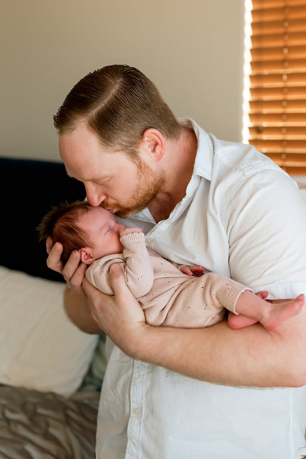 A tender moment of parent cradling and kissing their newborn baby.