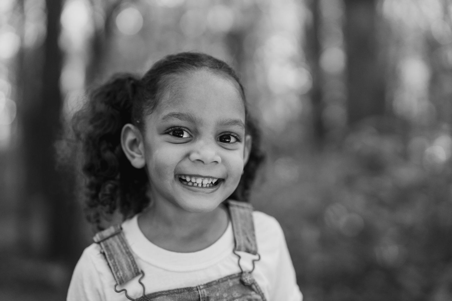 A natural portrait capturing a candid smile with curly hair outdoors.