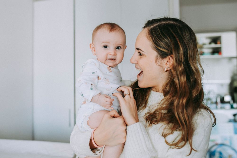 Sweet interaction between caregiver and baby in bright modern kitchen setting.