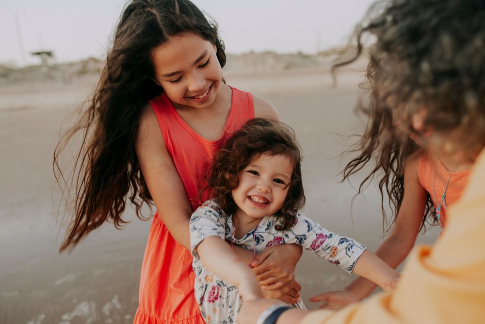 Candid moment of laughter and play on a sandy beach in warm evening light.