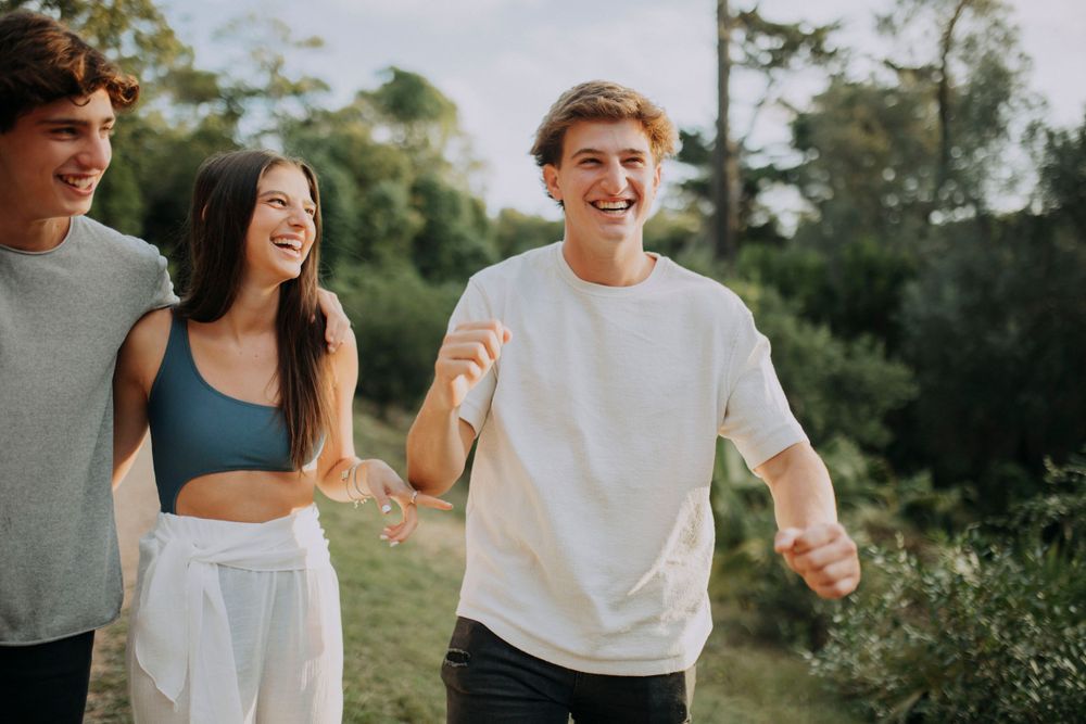Friends laughing and enjoying a sunny day outdoors in casual summer attire.