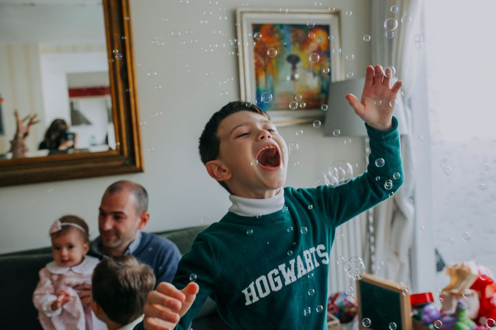 Energetic child in a hoodie shouting with excitement during an indoor gathering.