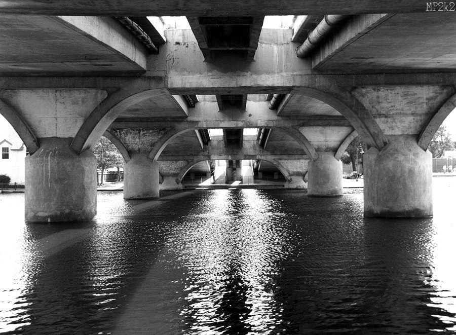 Geometric patterns of bridge supports reflected in dark water below.