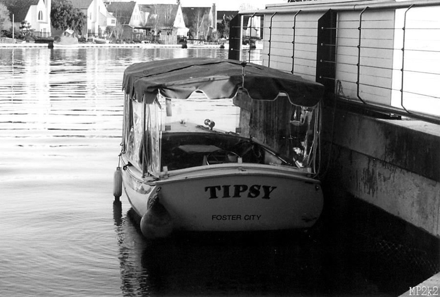 Black and white photo of a boat named Tipsy moored at a dock.