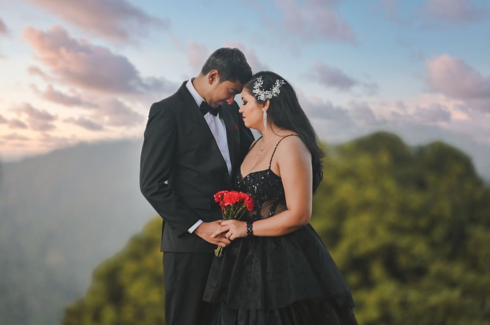 Romantic moment captured on scenic balcony with couple in black formal attire.