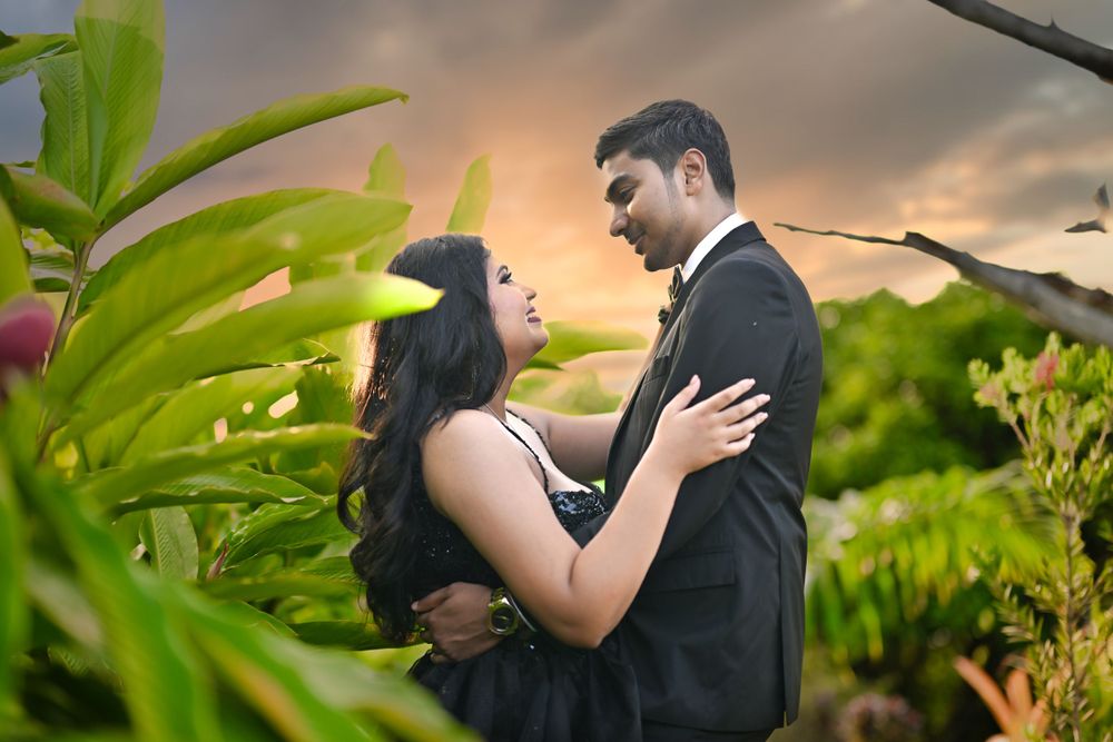 Intimate moment between couple surrounded by lush greenery at golden hour.