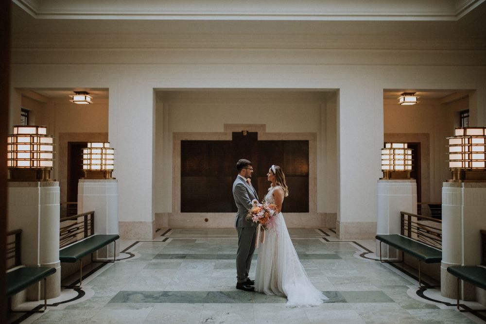 A couple shares an intimate moment in an elegant art deco style lobby at Hackney Town Hall, London.