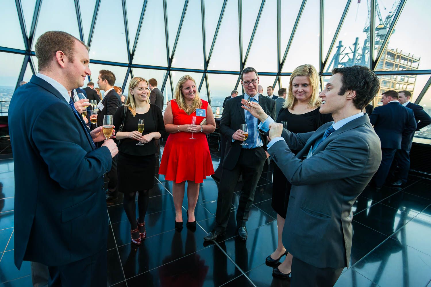 Guests mingling at a corporate drinks reception inside the glass dome of the Gherkin, London