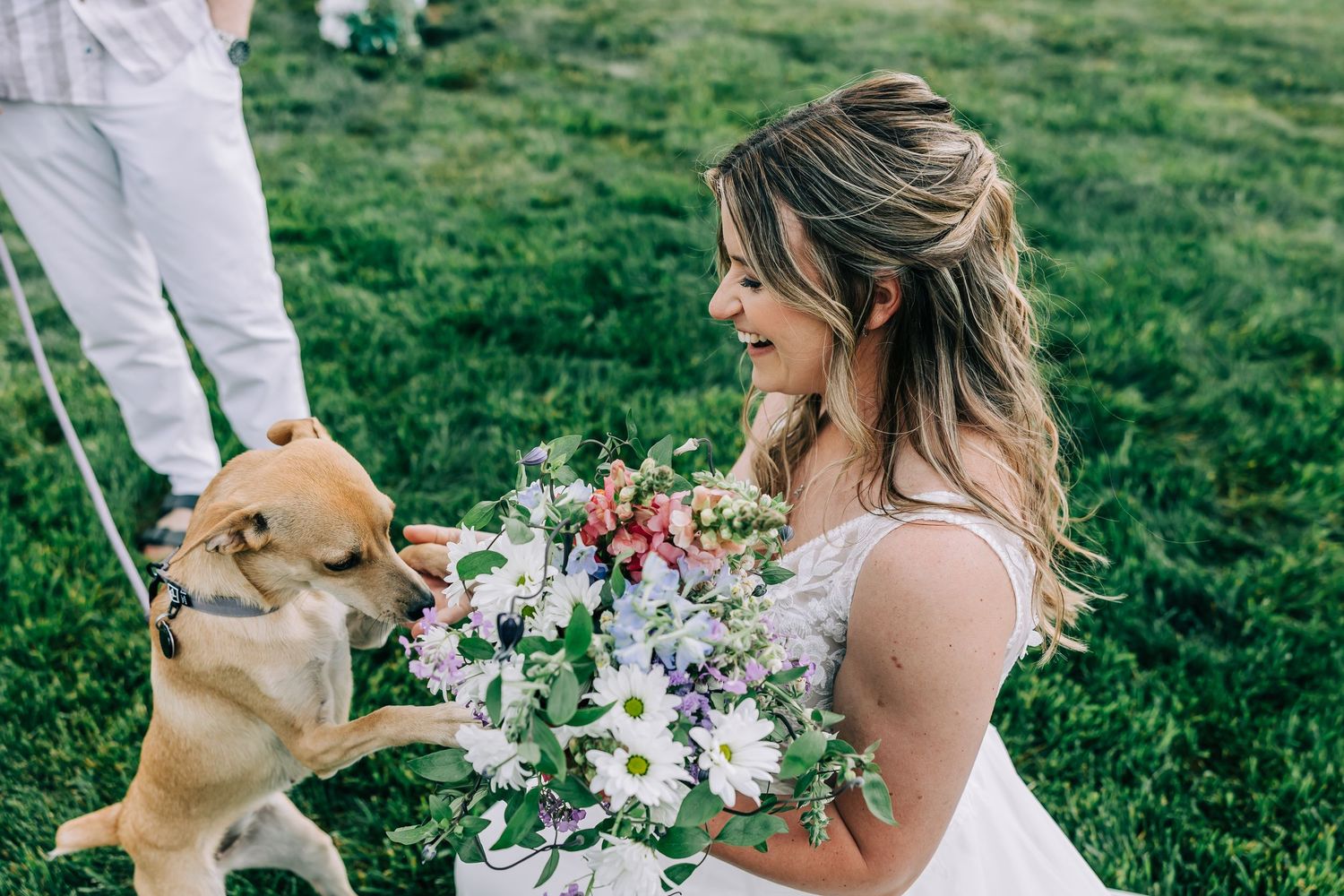 Bride holding her wedding bouquet while sharing a sweet moment with her dog during her Grand Teton elopement.