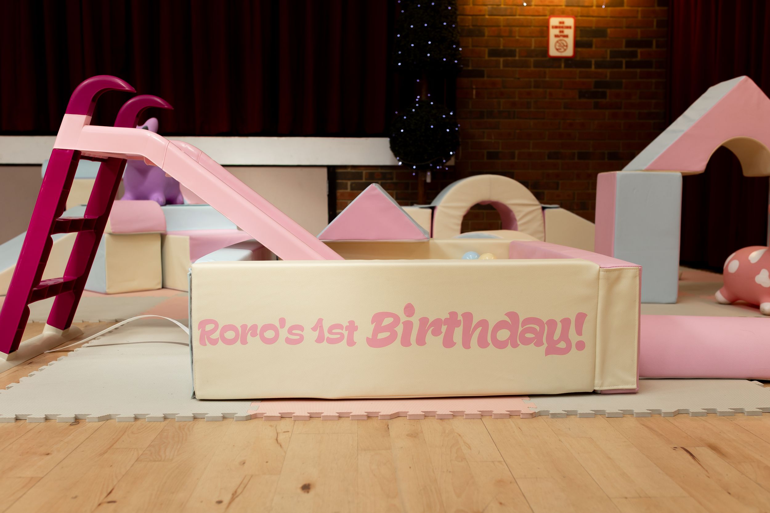 Soft play area with pink slide and foam blocks celebrating Roro's 1st Birthday party.