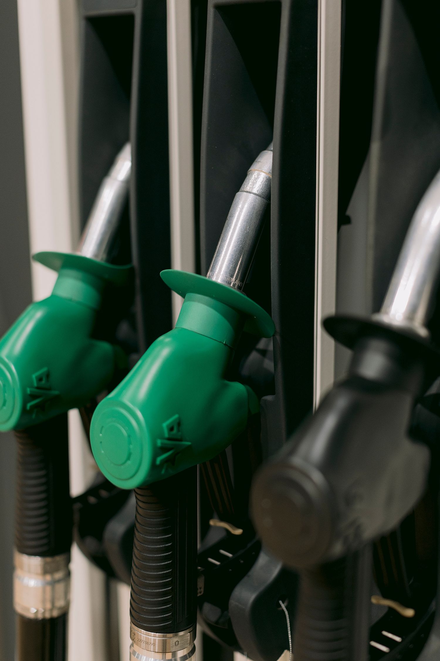 Close-up of green and black fuel pump nozzles at a gas station, ready for dispensing petrol or diesel.
