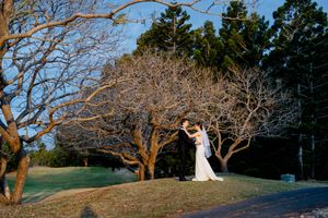 Bride and groom share a romantic dance outdoors among bare winter trees on a golf course at golden hour at Indooroopilly Golf Club Brisbane