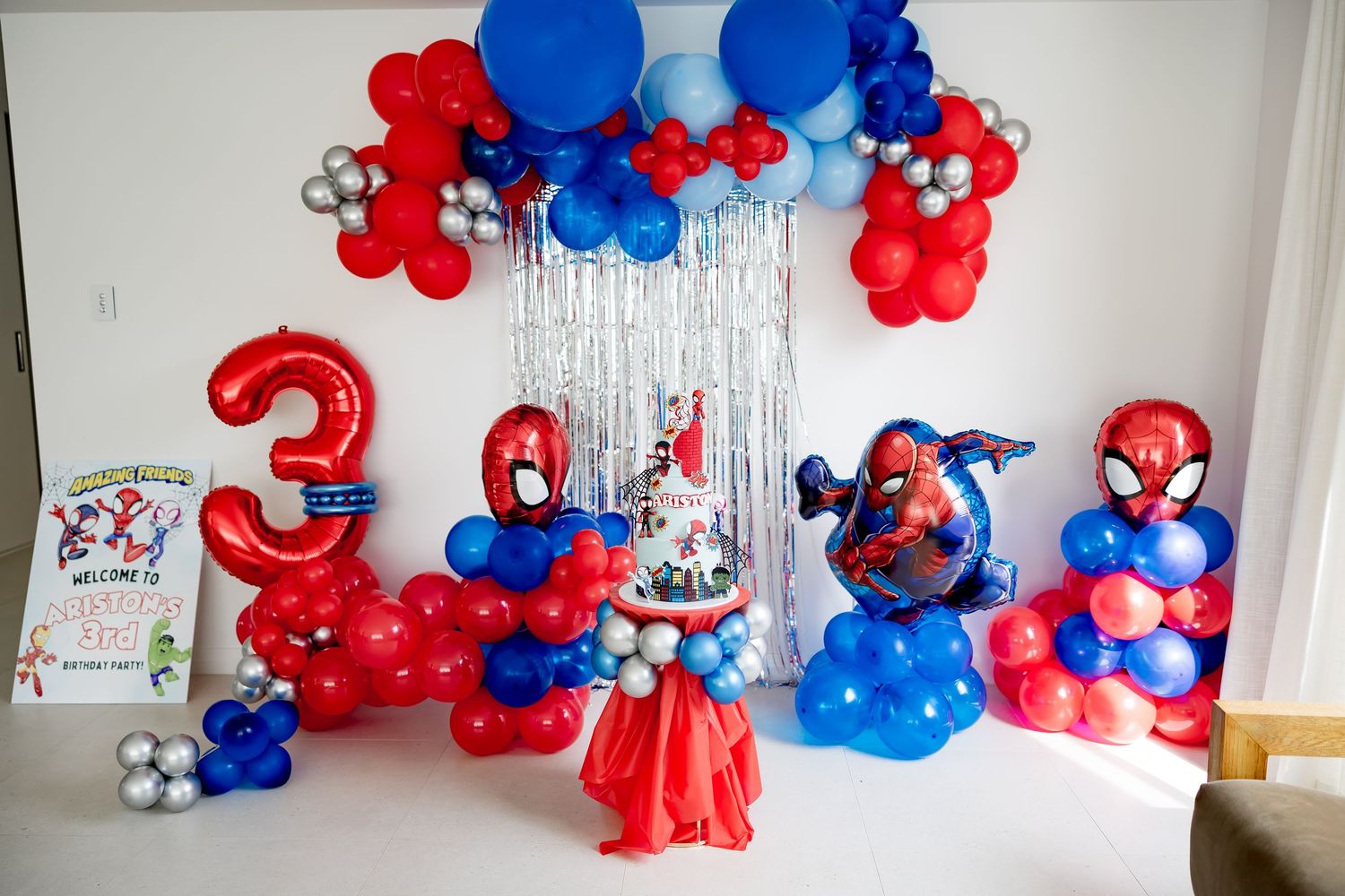 Spiderman themed 3rd birthday party setup with balloon arch, number balloons, and decorated cake table.